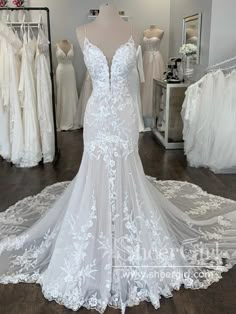 a white wedding dress on display in a bridal room with other dresses and gowns