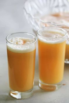 three glasses filled with liquid sitting on top of a table