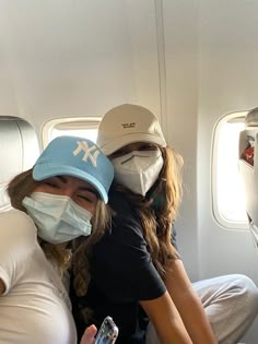 two women wearing face masks on an airplane