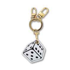 a white dice keychain with black dots on the front and sides, hanging from a gold - plated metal hook