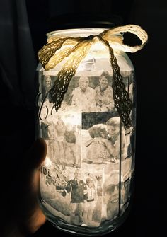 a hand holding a mason jar with pictures on it and a ribbon tied around the top