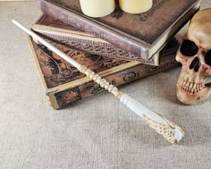 a skull with two candles on top of it next to some books and a wand