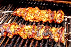 two skewers of meat cooking on a grill