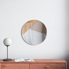 a round mirror sitting on top of a wooden dresser