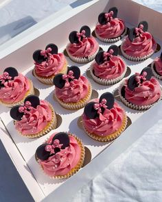 cupcakes with pink frosting and minnie mouse ears on them in a box