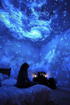 a person sitting on a bed under a sky filled with stars