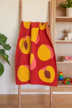 a red and yellow towel hanging on a wooden rack next to a potted plant