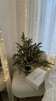 a small christmas tree sitting on top of a white ottoman