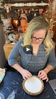 a woman in glasses is making a pie with white frosting on it's crust