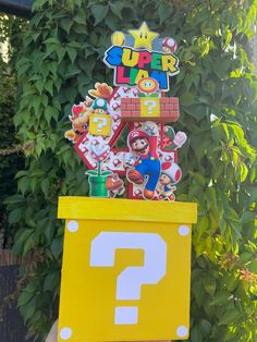 a super mario birthday party sign in the shape of a giant question mark on top of a yellow box