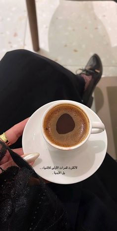 a person holding a cup of coffee in their left hand with writing on the saucer