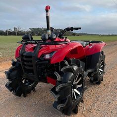 a red four wheeler parked on top of a dirt road