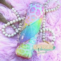 a pink and green drink sitting on top of a fluffy purple blanket next to a beaded necklace