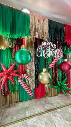 christmas decorations are hanging on the wall in front of an entrance to a building that is decorated with red, green and gold tinsels