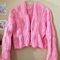 a pink knitted sweater hanging on a wall