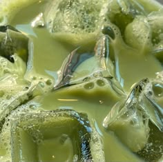 a mixture of green liquid in a bowl with ice cubes on the top and bottom