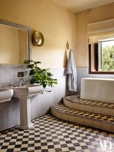 a bathroom with a checkered floor and black and white tiles on the floor, along with two sinks and a bathtub