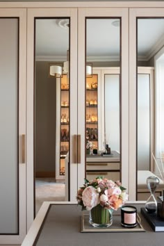 a vase with flowers and candles sitting on a table in front of mirrored closet doors