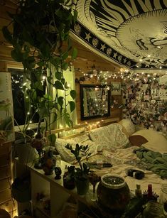 a living room filled with lots of plants and lights on the ceiling above it is a bed covered in blankets