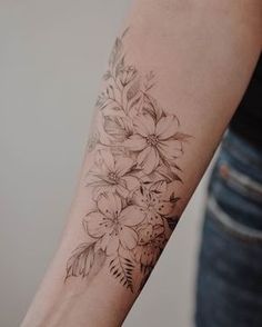 a woman's arm with flowers and leaves tattooed on the side of her arm