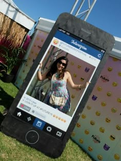 a woman standing in front of a giant cell phone with an instagram photo on it