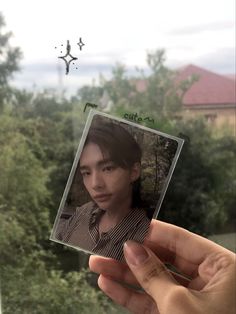 a person holding up a polaroid with trees in the background