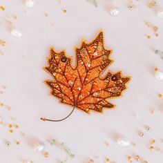 a close up of a leaf on a white surface with pearls and beads around it