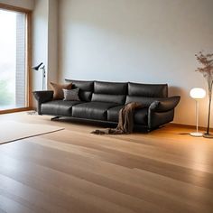 a living room with a black leather couch next to a large glass window and floor lamp