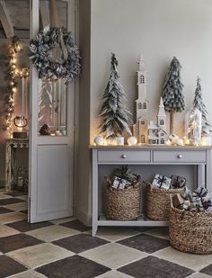 christmas decorations are displayed in baskets on the floor next to a table with candles and wreaths