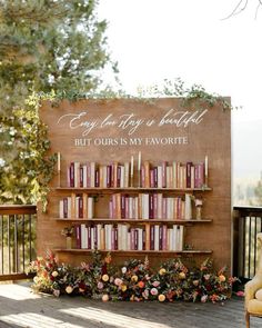 a book shelf with books on it and flowers in the foreground is decorated with greenery