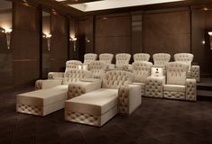 an empty theater with white chairs and footstools on the floor, in front of brown walls