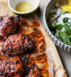 some meat is on a tray next to a bowl of salad and a glass of water