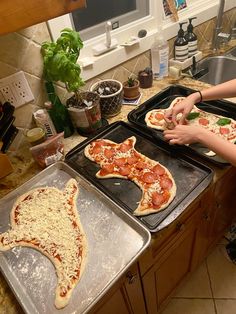 two people making pizzas in the kitchen