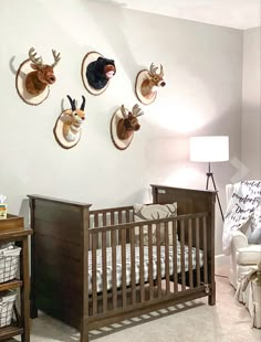 a baby's room with three deer heads mounted on the wall and two cribs