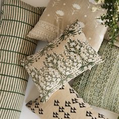 several pillows are stacked on top of each other with flowers in the middle one is green and white