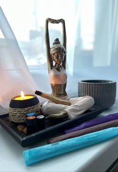 a statue sitting on top of a table next to a candle and some other items