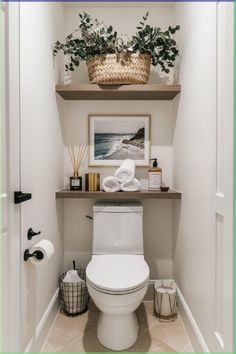 a white toilet sitting in a bathroom next to a shelf filled with towels and plants