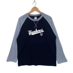 the yankees baseball shirt hangs on a hanger in front of a white wall with a black and gray t - shirt