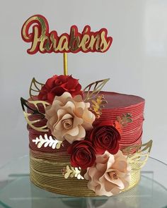 a red and gold cake with flowers on top that says parabiens in the center