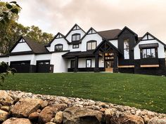 a large white and black house sitting on top of a lush green field