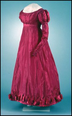 Woman's gown of cherry red plain-woven silk, trimmed with satin ribbon and self fabric shirring and piping. Gown has low, shallow neckline and raised waistline with in … 1800's Dress, Period Fashion, Romantic Era, Historic Fashion, Regency Period