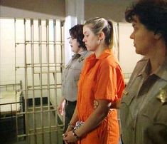 three women in orange prison uniforms standing next to each other