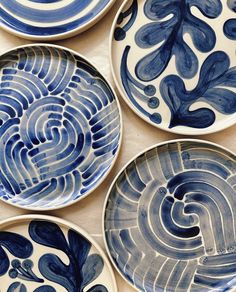 four blue and white plates with designs on them