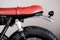 a close up of a motorcycle with a red seat and handlebars on it