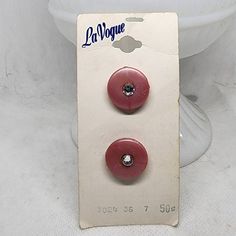 two red buttons sitting on top of a white toilet bowl next to a sign that says la voque