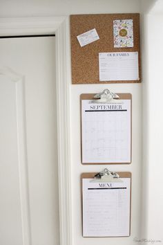 a cork board mounted to the side of a door with calendars and magnets on it