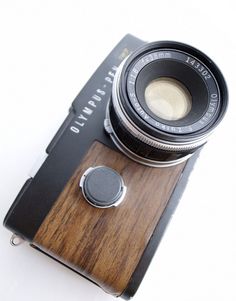 an old camera sitting on top of a wooden stand with a lens attached to it