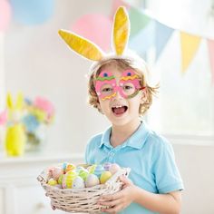 a little boy wearing bunny ears holding a basket with eggs in it and painted on his face