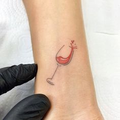 a small wine glass tattoo on the left inner arm and wrist, with a red liquid pouring out of it