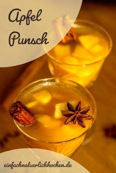 two glasses filled with anisel punch sitting on top of a wooden table next to cinnamon